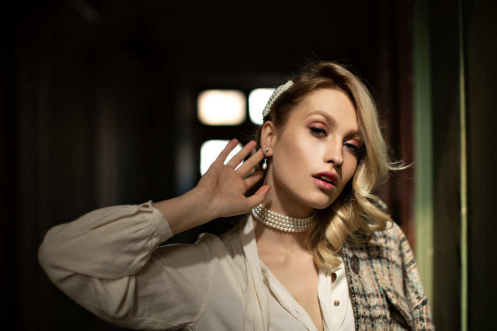 lady with beautiful makeup touches ear. pretty blonde woman in white blouse and checkered jacket lo